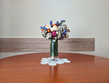Close-up of flower vase on table against wall at home