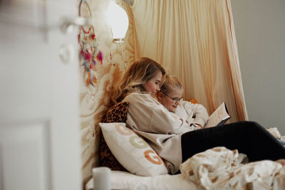 Mother reading book to daughter in bed