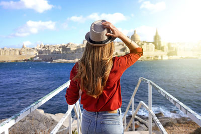 Back view of traveler girl walking on stairs enjoying view of valletta city, malta