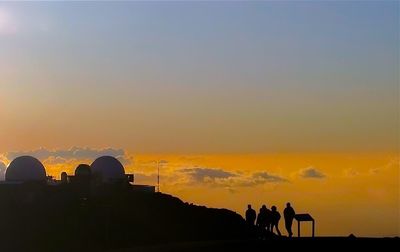 Silhouette people standing against orange sky