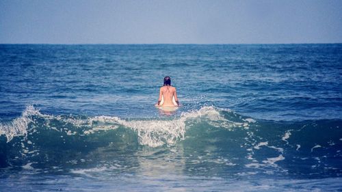 Rear view of a woman on surfboard in sea