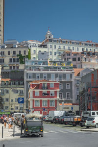 Cars on street by buildings against sky in city