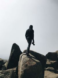 Rear view of man standing on rock against sky