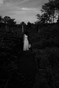 Woman standing on field against trees