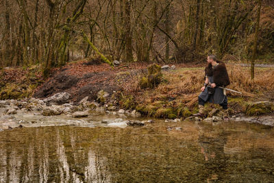 Men wearing costume standing on rock by stream in forest