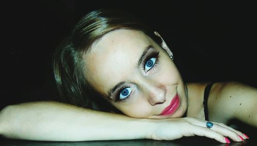 Close-up portrait of young woman against black background