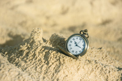 Close-up of clock on sand