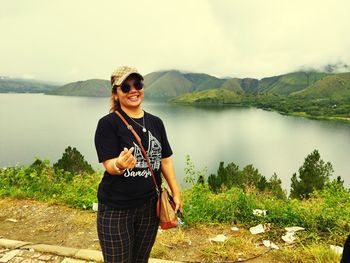 Portrait of young man standing against lake