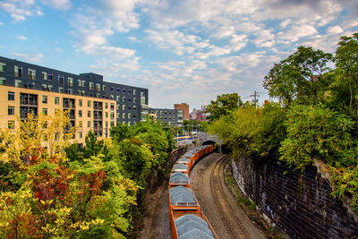 Road by buildings in city against sky