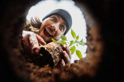 Excited male gardener planting flower. view from hole from bottom up. looking to the camera