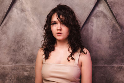 Portrait of young woman standing against wall