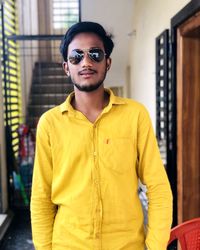 Portrait of young man wearing sunglasses standing in corridor