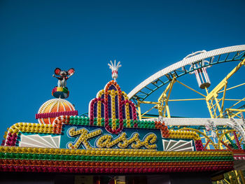 Low angle view of amusement park against blue sky