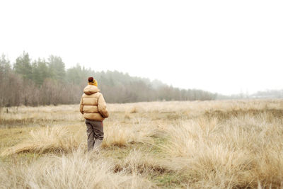 Rear view of man standing on field against sky