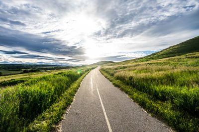 Road amidst green landscape against sky