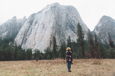 Rear view of woman standing on mountain against sky