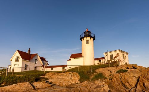 Lighthouse by building against clear blue sky