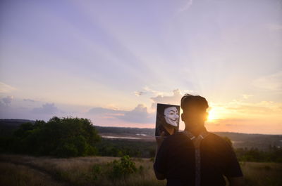 Man standing by plants against sky during sunset