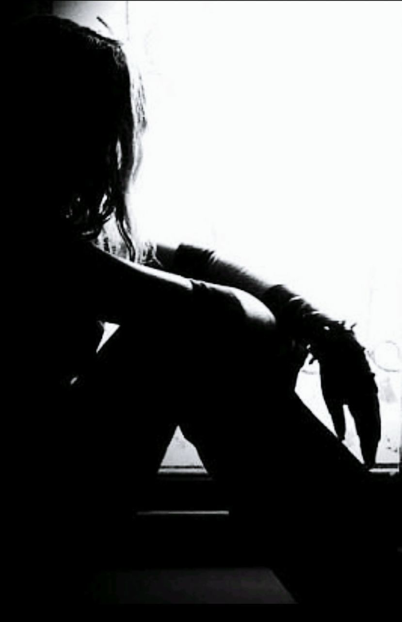 PORTRAIT OF A SILHOUETTE WOMAN SITTING ON WALL