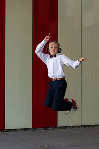 Full length of girl standing against red wall