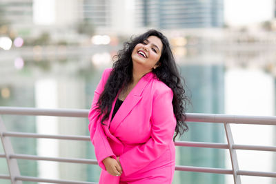 A modern indian girl in an elegant suit walks along the marina dubai embankment and smiles