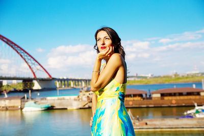 Side view of smiling woman looking away while standing against sky