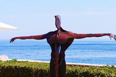 Statue by sea against sky