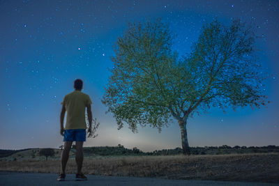 Rear view of man standing on field against sky