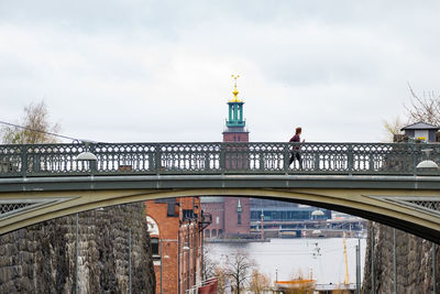 Person jogging over bridge against stockholm city hall
