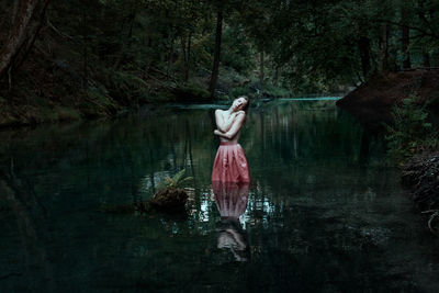 Rear view of woman in lake at forest