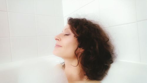 Happy woman relaxing in bathtub at home