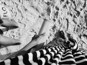 Low section of woman holding mat at beach