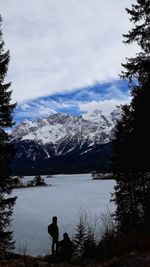 Man looking at lake by mountain against sky