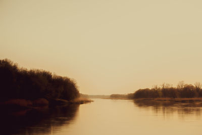 Scenic view of lake against clear sky during sunset