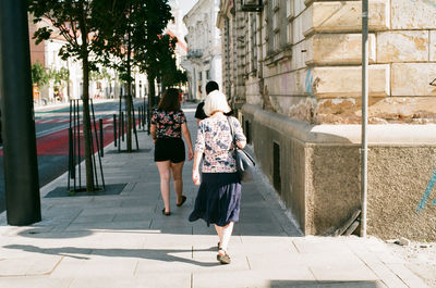 Rear view of women walking on footpath