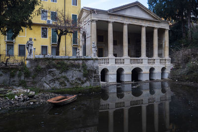 Arch bridge over canal by buildings in city