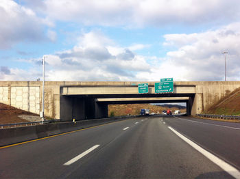 Road leading towards highway against sky