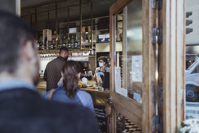 Customers maintaining social distancing while collecting order from deli store during pandemic