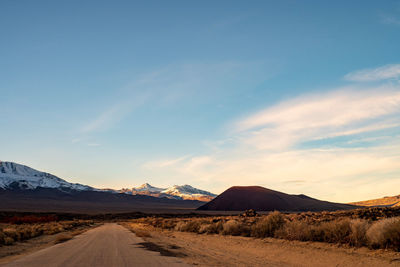 Dirt road in desert against sky