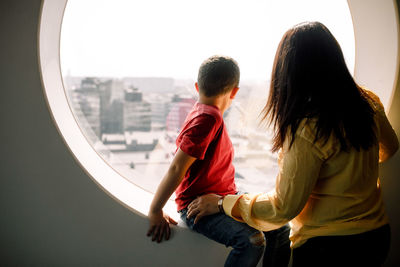 Mother and son looking through window from hotel room