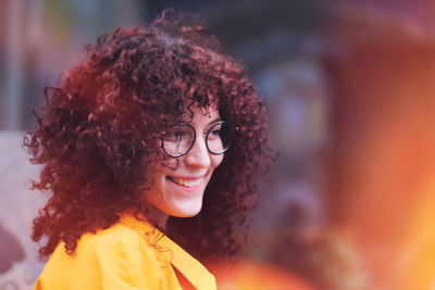 Smiling young woman looking away standing against blurred background