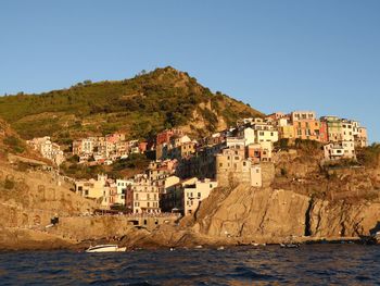 Buildings by sea against clear blue sky