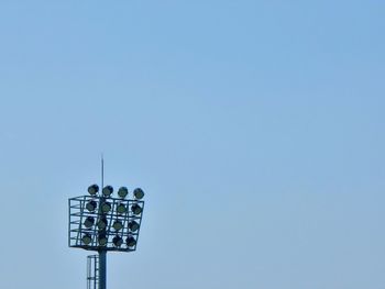 Low angle view of security camera against clear blue sky