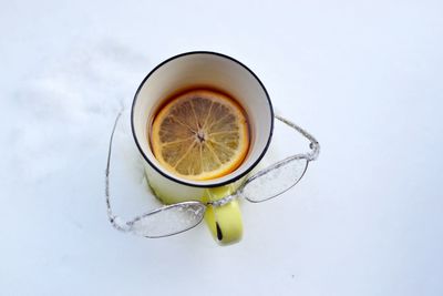 Close-up of drink in cup with eyeglasses on snow