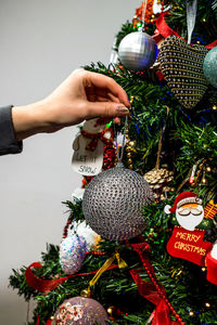 Close-up of hand holding christmas decoration hanging on tree
