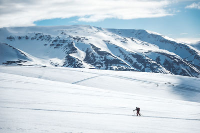 Man backcountry skiing on ski tracks with mountain in background