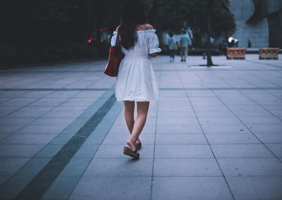 Rear view of woman walking on footpath