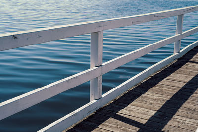 Part of wooden pier in front of blue water