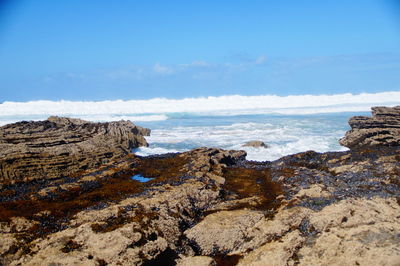 Rock formations on beach against sky