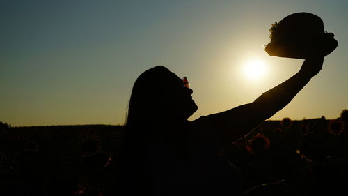 Silhouette man on field against sky during sunset